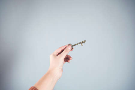 woman hand holding vintage key on gray backgroundの写真素材