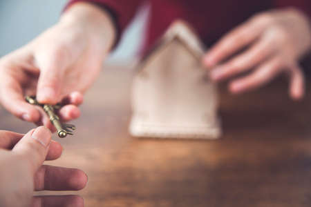 womans hands holding key with house model on desk