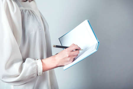 woman hand holding notepad on gray background
