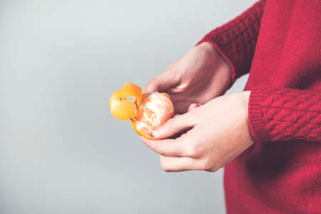 woman hand mandarin on the gray backgroundの写真素材