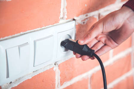 A woman hand pulls a black cord in home