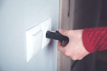 A woman hand pulls a black cord in home
