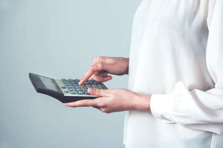 women hand holding calculator on gray wall backgroundの写真素材