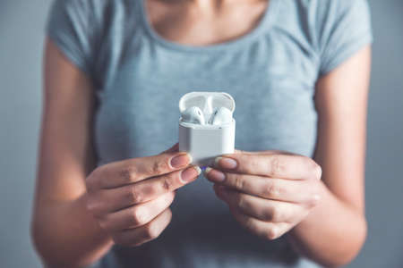 woman hand holding white earphone on gray backgroundの写真素材