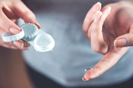 woman hand holding optical lenses on gray backgroundの写真素材