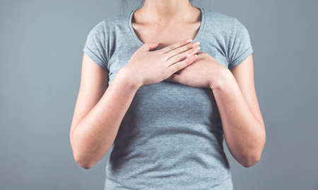 woman hand on heart on the gray wall bakgroundの写真素材