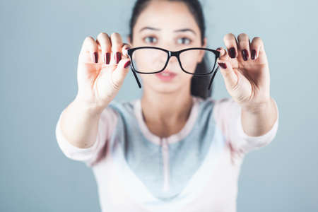 Woman holding glasses on the gray background