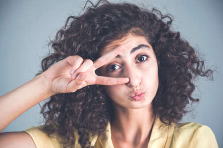 young woman hand victory sign in eyeの写真素材