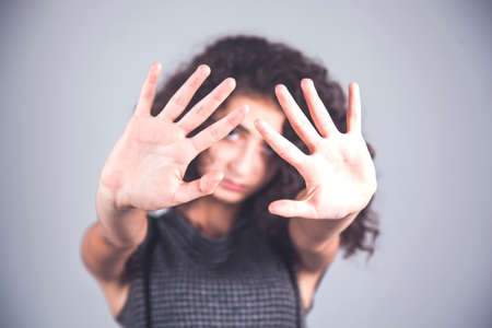 sad woman hand stop  sign on grey backgroundの写真素材