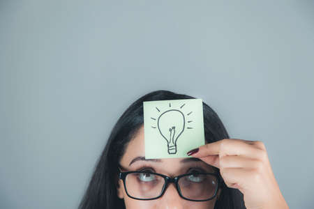 young woman hand drawing bulb in headの写真素材