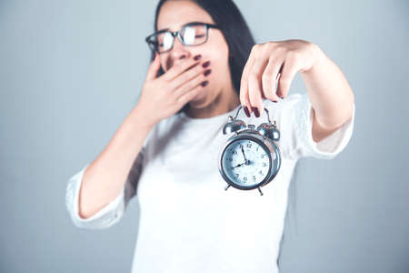 tired woman hand  clock on gray background