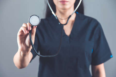 woman doctor hand stethoscope on dark backgroundの写真素材