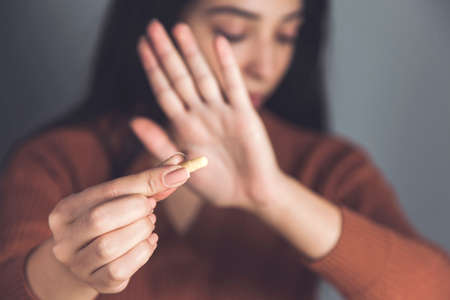 woman hand stop sign in pill on dark background