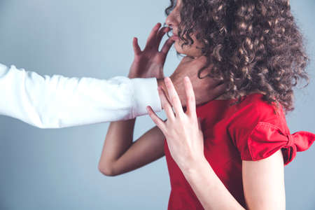 man choke woman on the gray wall backgroundの写真素材