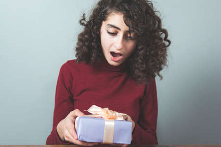 young surprised woman hand holding gift boxの写真素材