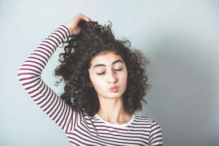 crazy woman hand in hair on gray wall backgroundの写真素材