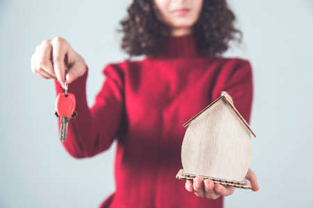 happy woman hand holding key with house modelの写真素材