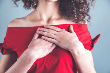 woman hand on heart on grey backgroundの写真素材