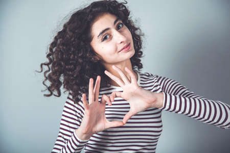 woman hand heart sign on grey background