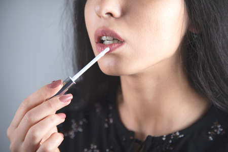 woman Apply lipstick to lips on grey backgroundの写真素材