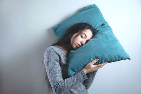 sad tired woman hand pillow on grey backgroundの写真素材