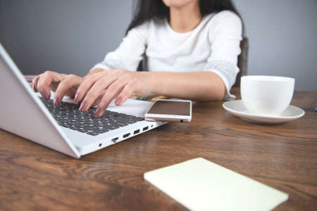  woman hand phone with coffee and computer on deskの写真素材