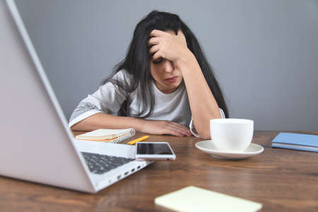 sad woman hand phone with coffee and computer on deskの写真素材