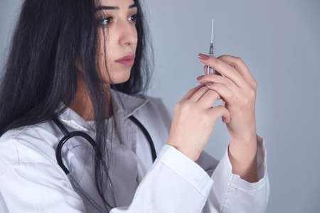 Doctor hand holding syringe on grey backgroundの写真素材