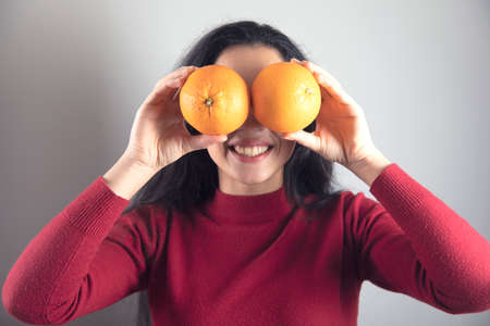 happy woman hand orange in eye on grey backgroundの写真素材