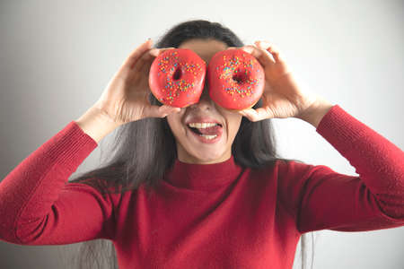 happy woman hand Donut in eye on grey background