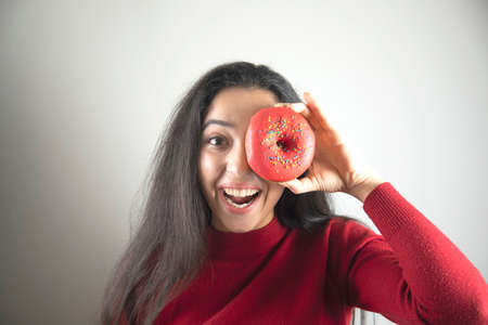happy woman hand Donut in eye on grey backgroundの写真素材