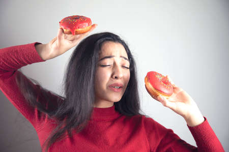 happy woman hand holding  Donut on grey background