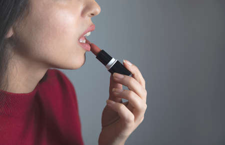 happy woman hand holding lipstick on grey backgroundの写真素材