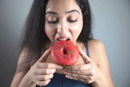happy woman eat Donut on grey backgroundの写真素材