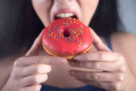 happy woman eat Donut on grey backgroundの写真素材