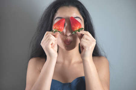 happy woman hand holding strawberries in eyeの写真素材