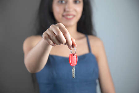 woman hand holding house key on grey backgroundの写真素材