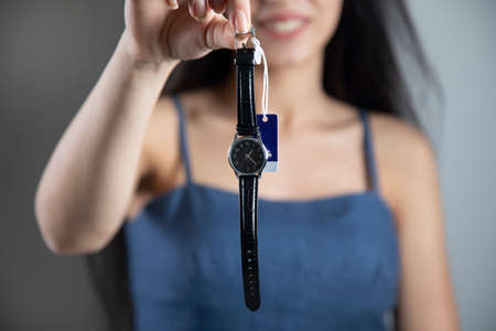 woman hand holding black watch on grey backgroundの写真素材