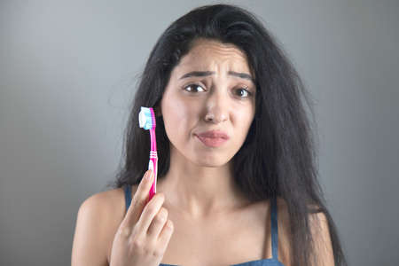 Woman Brush your teeth with a toothbrush on grey backgroundの写真素材