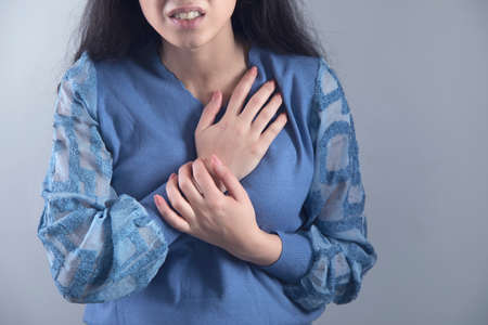 woman hand in ache heart on grey background