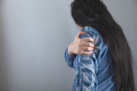 young woman hand in ache hand on grey backgroundの写真素材