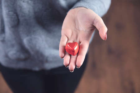 young woman hand holding candies red heart の写真素材