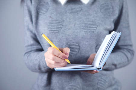 woman hand holding blue notepad on grey background