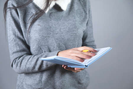 woman hand holding blue notepad on grey background
