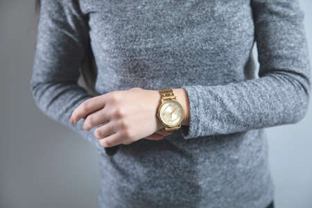 young woman hand clock on grey backgroundの写真素材