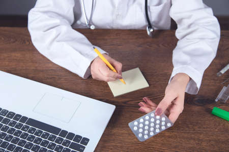 Doctor writing recipe and computer on deskの写真素材
