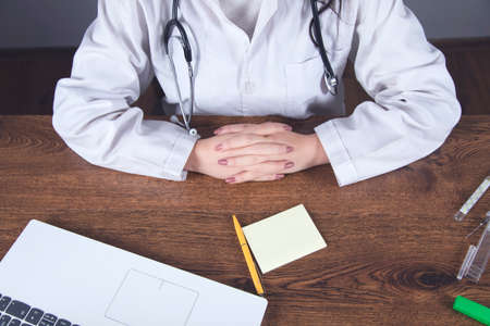 Doctor writing recipe and computer on desk