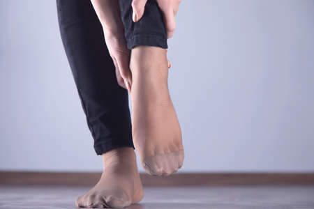 woman hand in ache feet on dark backgroundの写真素材