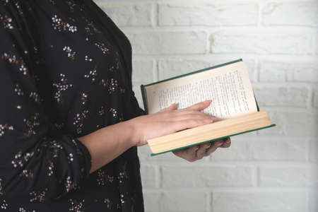 young woman hand holding green book on brick wall backgroundの写真素材