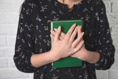 young woman hand holding green book on brick wall background
